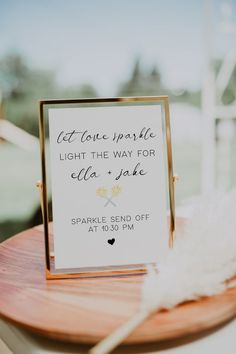 a sign that is sitting on top of a wooden table next to a white feather