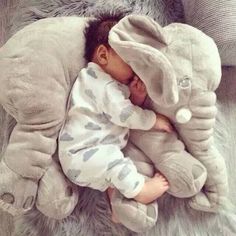 a baby sleeping on top of an elephant pillow