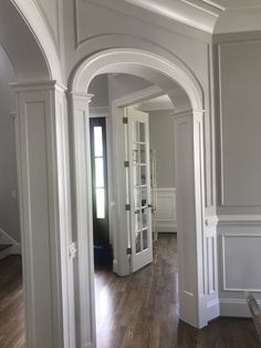 an archway leads into a living room with hardwood floors and white trim on the walls