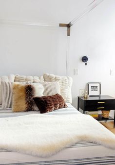 a white bed topped with lots of pillows next to a night stand and nightstands