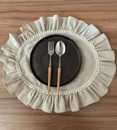 a black plate topped with two silverware on top of a wooden table