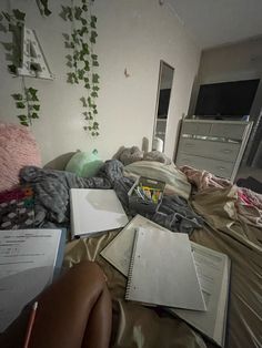 an unmade bed with books and papers on it