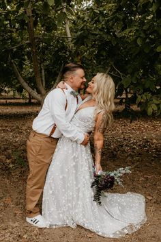 a bride and groom kissing in front of some trees