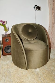 a green chair sitting on top of a carpeted floor next to a book shelf