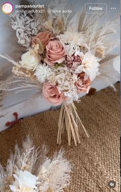 a bouquet of flowers sitting on top of a bed next to two feathers and roses