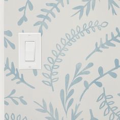 a light switch cover with blue leaves and branches painted on the wall next to it