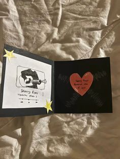 an open book with writing on it and a red heart in the middle, sitting on a bed