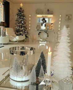 a white christmas tree sitting on top of a table next to a glass candle holder