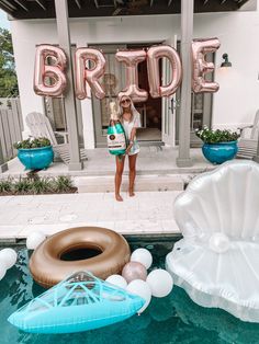 a woman standing in front of a pool with balloons and an inflatable raft