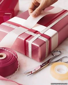 a person is wrapping a gift with tape and scissors