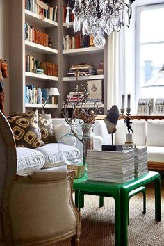 a living room filled with lots of furniture and a chandelier hanging from the ceiling