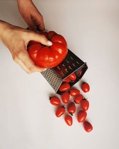 a person grating tomatoes with a grater on a white counter top next to them