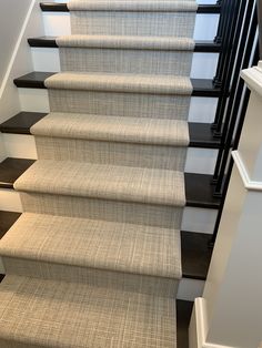 a carpeted staircase with black handrails and white stairs