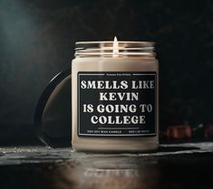 a candle is sitting on a table with a quote printed on it that says smells like kevin is going to college