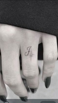 a person's hand with a small tattoo on the middle finger and an arrow in the middle