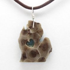 a brown and white necklace with a blue stone in the shape of a heart on a leather cord