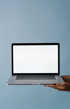 a person holding a laptop with a blank screen in their hand on a blue background