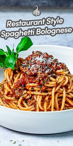 spaghetti with sauce and parmesan cheese in a white bowl on top of a table