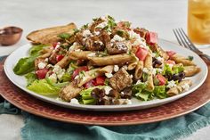 a plate full of pasta salad with chicken, tomatoes, lettuce and feta cheese