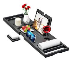 a black tray with flowers, candles and pictures on it is sitting next to a glass of red wine