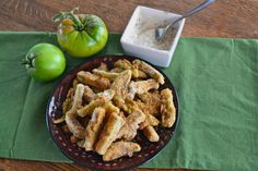 some fried food is on a plate next to an apple and a bowl of dip