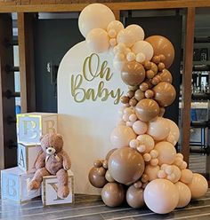 a teddy bear sitting on top of a table next to some balloons and letters that spell out oh baby