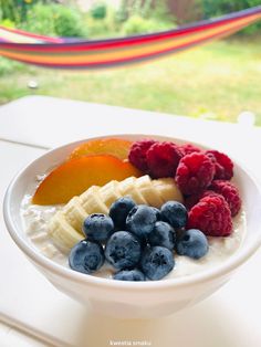 a bowl filled with yogurt and fruit on top of a white table next to a hammock