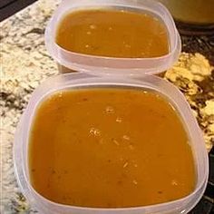 two plastic containers filled with soup sitting on top of a counter next to an oven