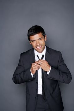 a man in a suit and tie is posing for a photo with his hands together