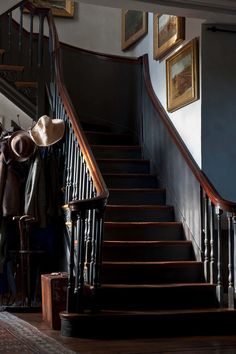 there is a hat on the banister next to some clothes and coat hangers