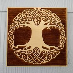 a wooden plaque with an image of a tree in the center and celtic knots around it