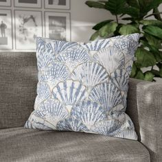 a blue and white pillow sitting on top of a couch next to a green plant