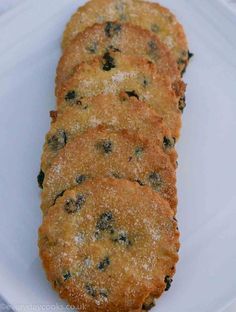 four cookies on a white plate with powdered sugar and blueberries in the middle