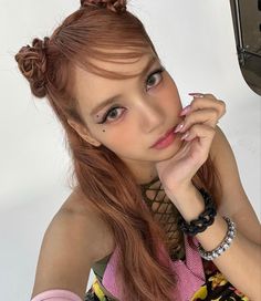 a woman with long red hair is posing for the camera and has her hand on her chin