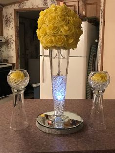 a vase filled with yellow flowers sitting on top of a counter next to two crystal bowls