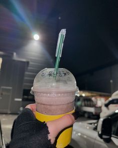 a person holding up a cup with a straw in it