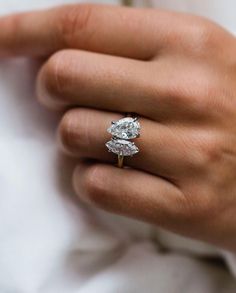 a close up of a person's hand wearing a ring with a diamond on it