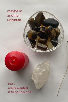 a bowl filled with rocks next to a candle on top of a white tablecloth