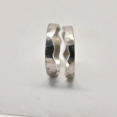 two silver rings sitting next to each other on a white surface and one is missing the middle