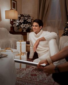 a man sitting on the floor in front of christmas presents with his hands out to him