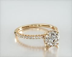 a yellow gold engagement ring with an oval cut diamond and pave set side stones