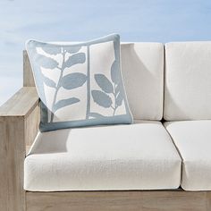 a white couch sitting on top of a wooden table next to a blue and white pillow