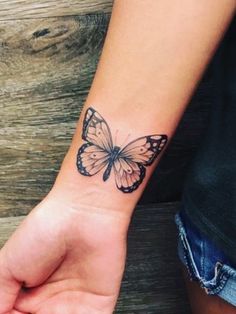 a woman's wrist with a small butterfly tattoo on the left side of her arm