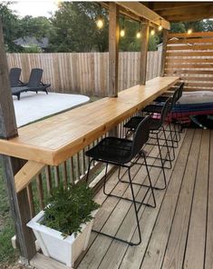 a wooden deck with chairs and plants on it, next to a fenced in area