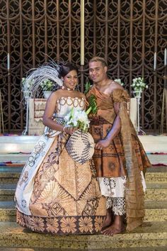 a man and woman dressed up in traditional african wedding attire standing next to each other