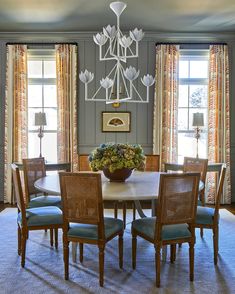 a dining room table with chairs and a chandelier hanging from the ceiling above it