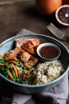 a bowl filled with rice, meat and veggies on top of a wooden table