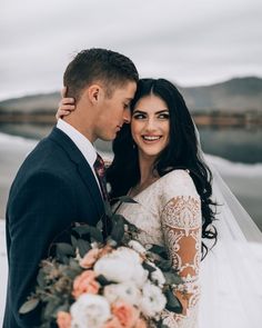 a bride and groom standing next to each other in front of the water on their wedding day