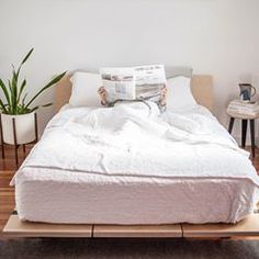 a bed with white sheets and pillows on top of it in a room that has hardwood floors