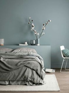 a bed sitting next to a blue wall in a bedroom